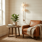 The lit sconce above a side table and a leather armchair with a throw
