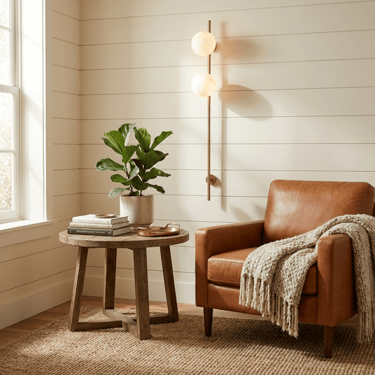 The lit sconce above a side table and a leather armchair with a throw