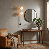 The lit sconce beside a round mirror above a console in an entry