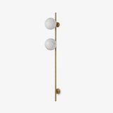 Tall slim rod wall sconce with two round stone globes on a pale wall