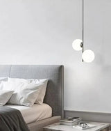 Opal globes lit beside a bed with a soft upholstered headboard