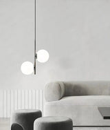 Two globes hung in a pale corner above the arm of a pale gray sofa
