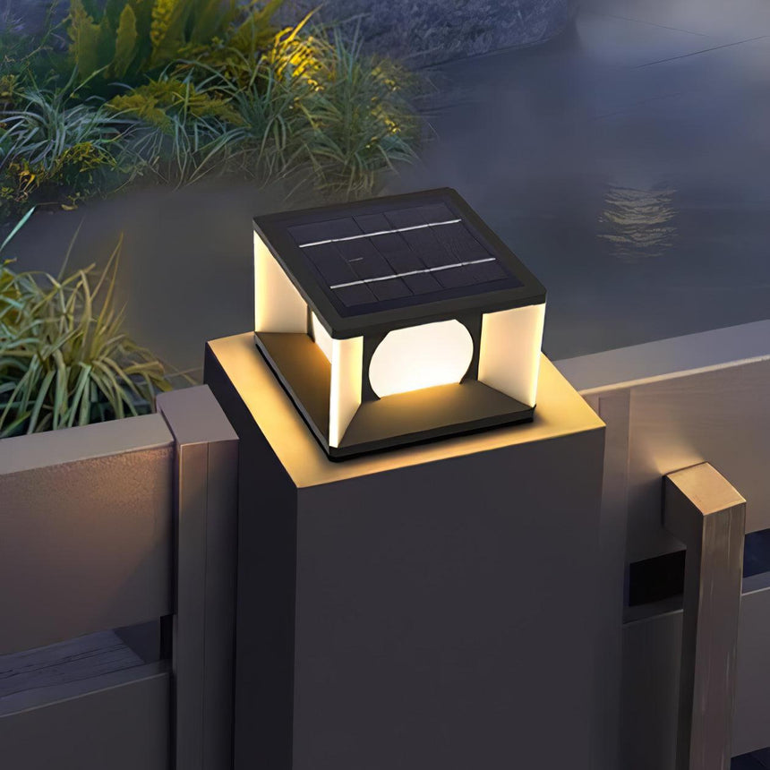 The cube lit on a concrete pillar with ornamental grasses beside it