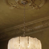 The stone drum hung below a plaster ceiling rose on a chain