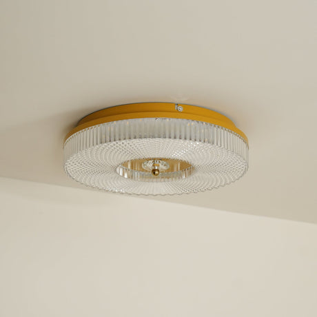 Ribbed drum ceiling light with a brass rim against a plain wall