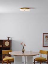 Ribbed drum ceiling light above a round dining table with yellow chairs