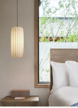 Ribbed silk column lit beside a bed in a calm bedroom