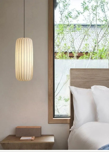 Ribbed silk column lit beside a bed in a calm bedroom