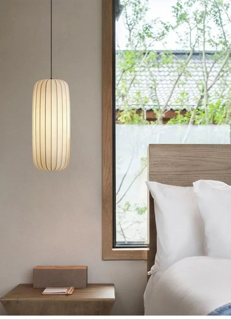 Ribbed silk column lit beside a bed in a calm bedroom