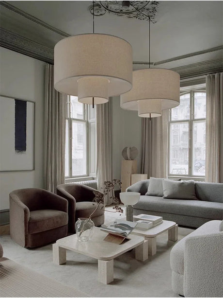 Two drum shade pendant lights lit in a large living room