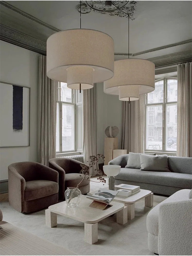 Two drum shade pendant lights lit in a large living room