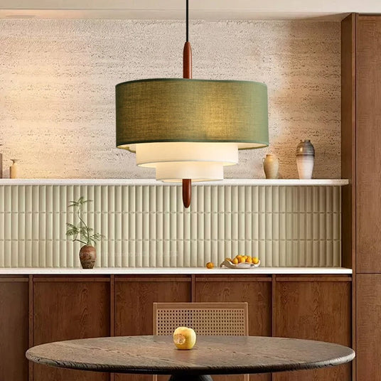 Tiered drum shade above a round dining table in a room with a wood sideboard