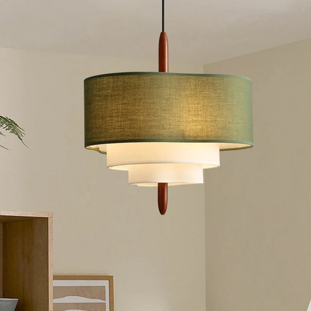 Three tier drum shade pendant light in olive and cream fabric above a pale table