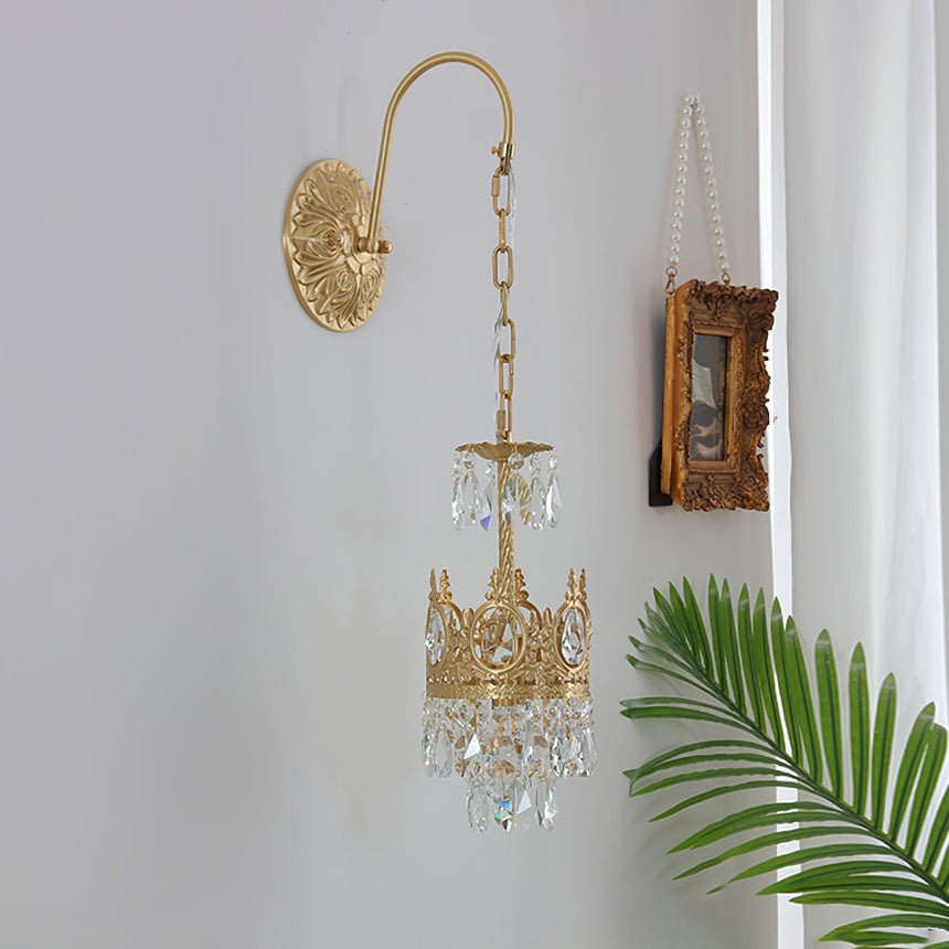 The sconce beside a small framed picture and a palm leaf on a pale wall