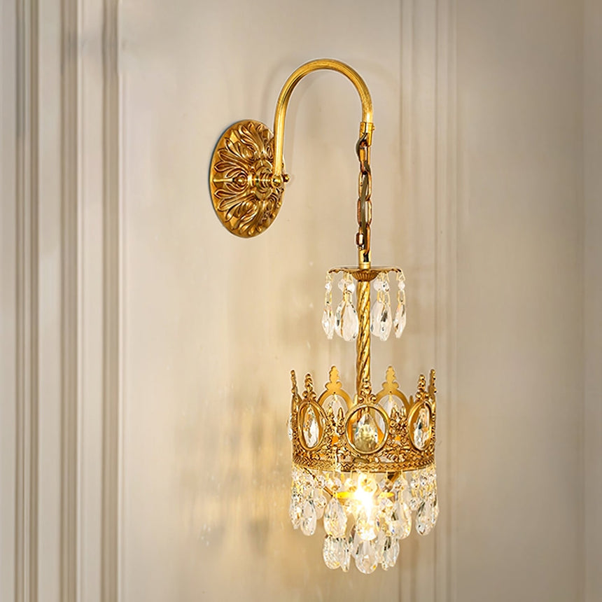 The crown sconce lit on a white paneled wall with molding