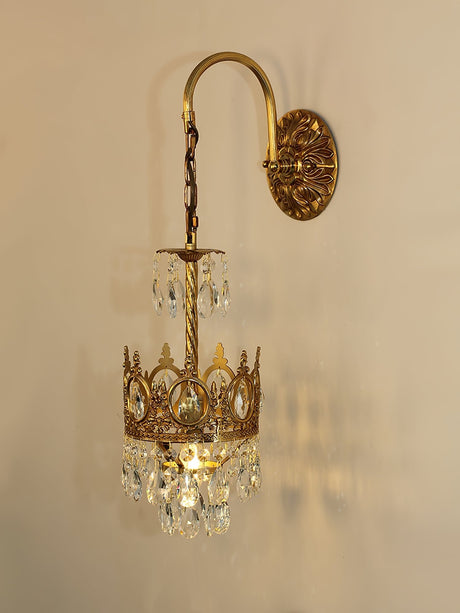 The crown lit warm on a beige wall, the crystal drops glowing