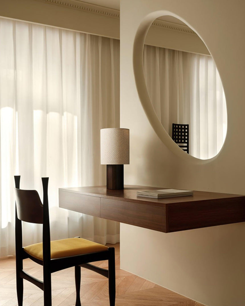 Entryway table lamp on a floating shelf below a round wall mirror