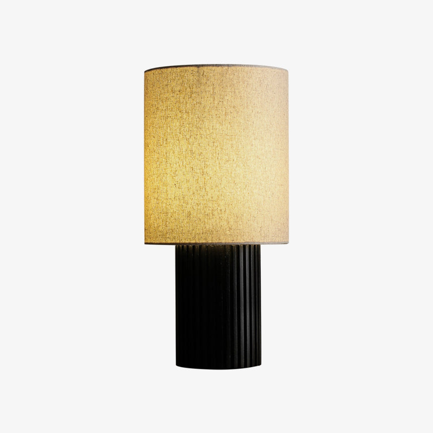 Black entryway table lamp lit and seen from the front, plain background