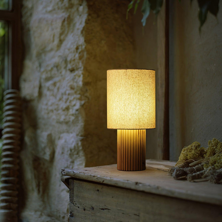 Entryway table lamp lit on a stone ledge against a rough plaster wall
