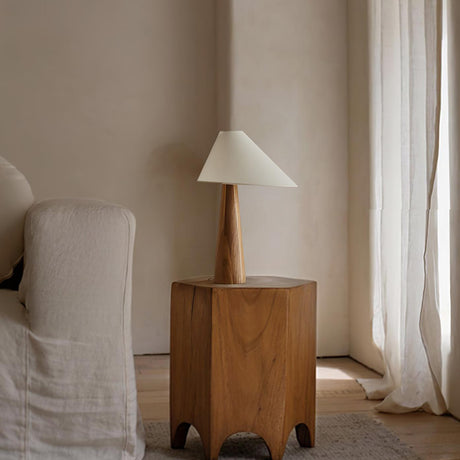 Wood cone lamp unlit on a wood stool beside a pale armchair