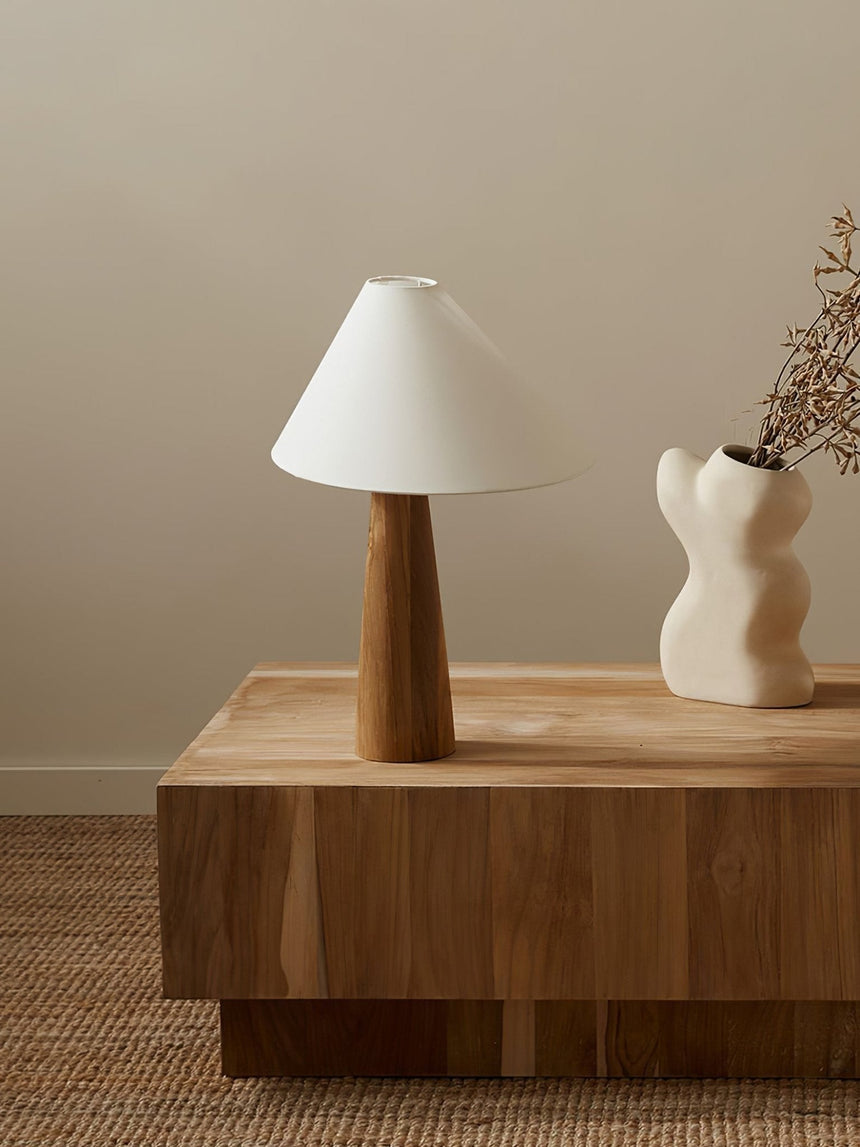 Wood cone lamp unlit on a solid wood block beside a white vase