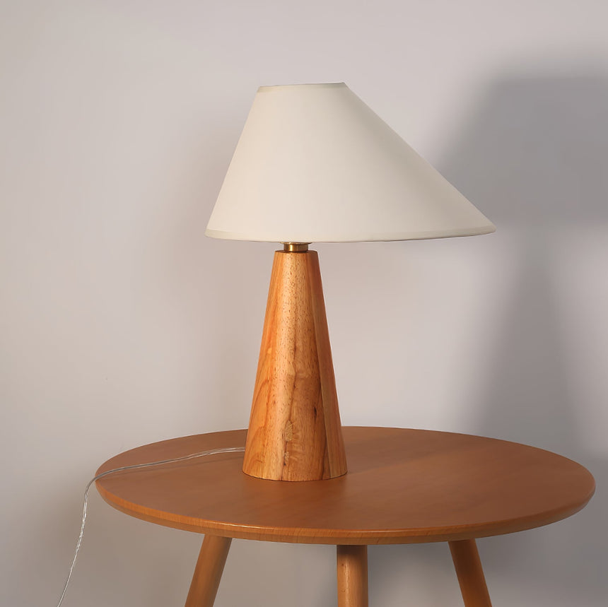 Wood cone lamp unlit on a round wood table against a pale wall