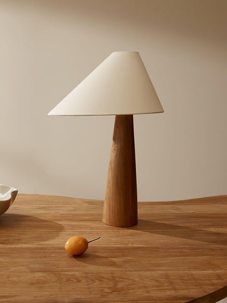 Linen wood cone lamp unlit on a round wood table beside a small bowl