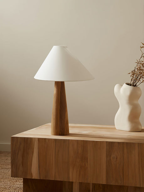 Wood cone lamp unlit on a wood block beside a curved white vase
