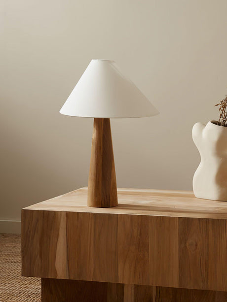 Wood cone lamp unlit on a console beside books and reading glasses