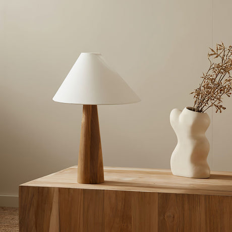 Wood cone lamp unlit beside dried branches in a white vase