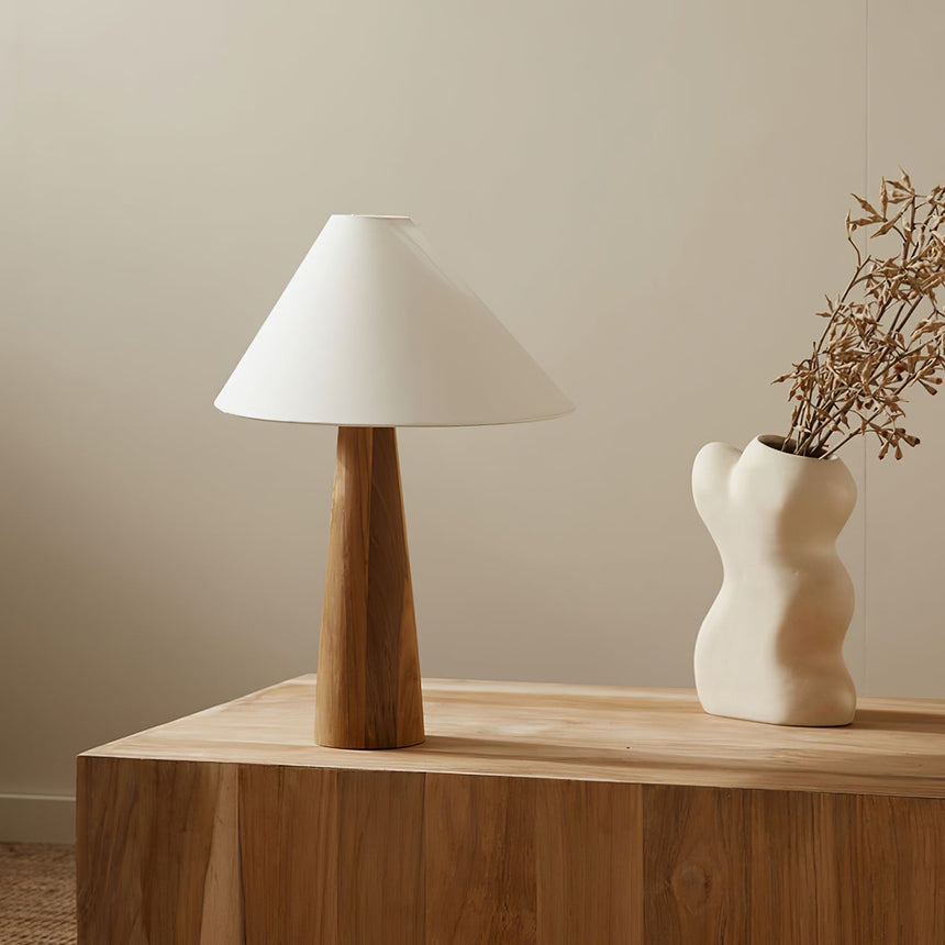 Wood cone lamp unlit beside dried branches in a white vase