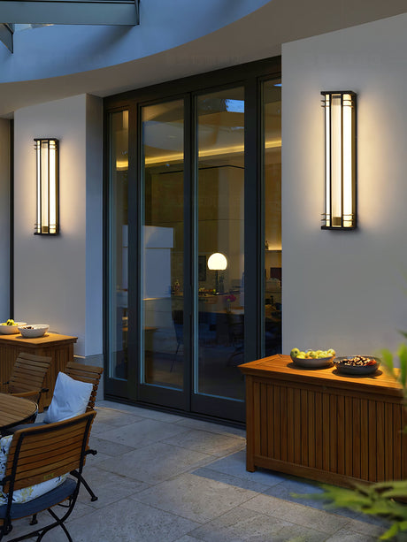 Two box lights beside glass patio doors above an outdoor dining table and chairs