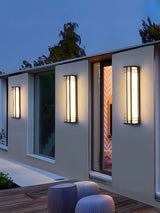 Box lights of two lengths lit along a house wall above a terrace with stools