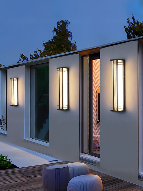 Box lights of two lengths lit along a house wall above a terrace with stools