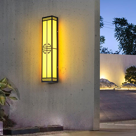 The lantern lit on a courtyard wall at dusk, a paved garden beyond the opening
