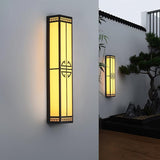 The lantern on a white wall, a second one on a far wall above a clipped pine