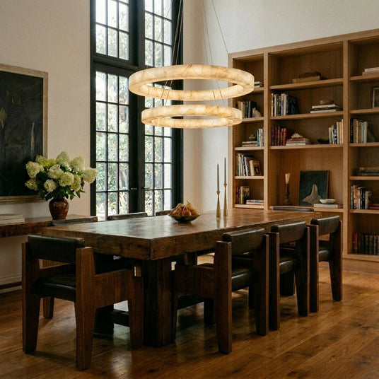 Three lit rings above a long timber dining table and chairs