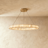 A single lit alabaster ring on four thin cables below a brass plate