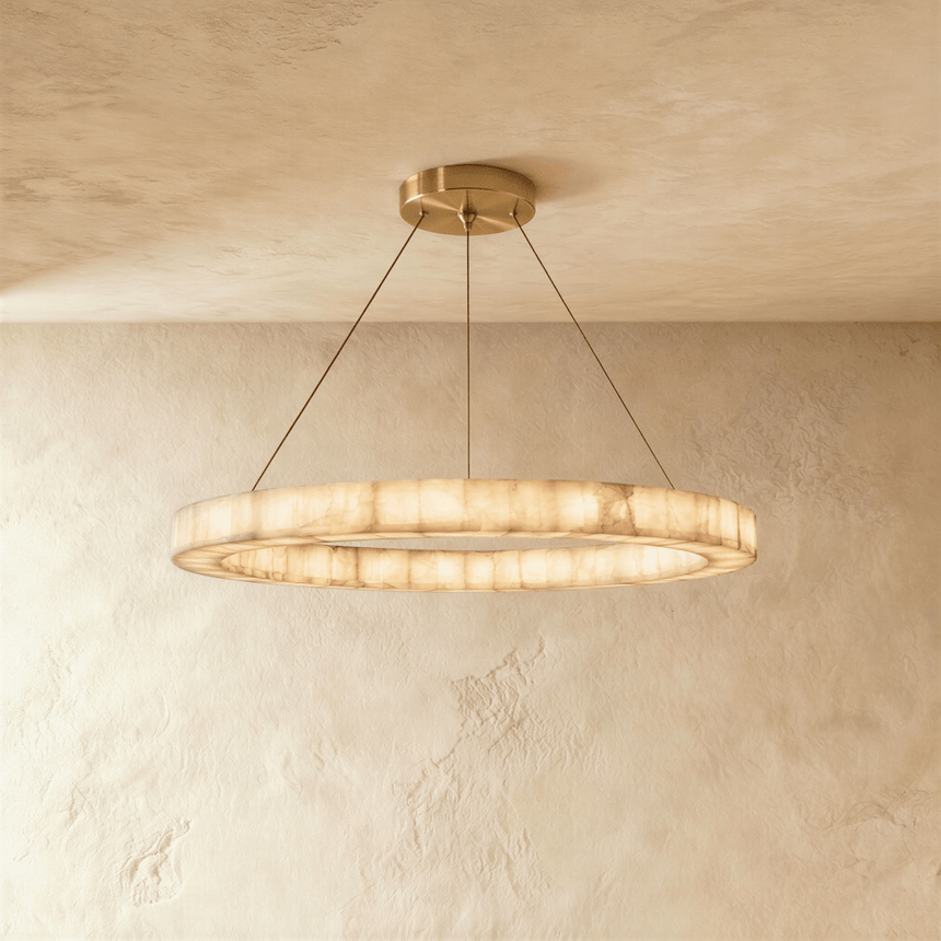 A single lit alabaster ring on four thin cables below a brass plate