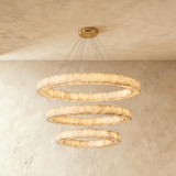 Three stacked alabaster rings lit on thin cables under a brass plate
