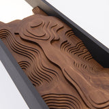 The wood face carved in layered contour lines like a relief map