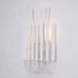 White wood rods of uneven height standing on looped wire, seen straight on