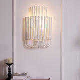 Rod sconce lit warm on a paneled wall, the light spilling upward