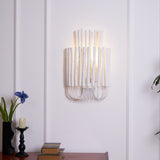 Rod sconce lit on a paneled wall above a table with books and candles