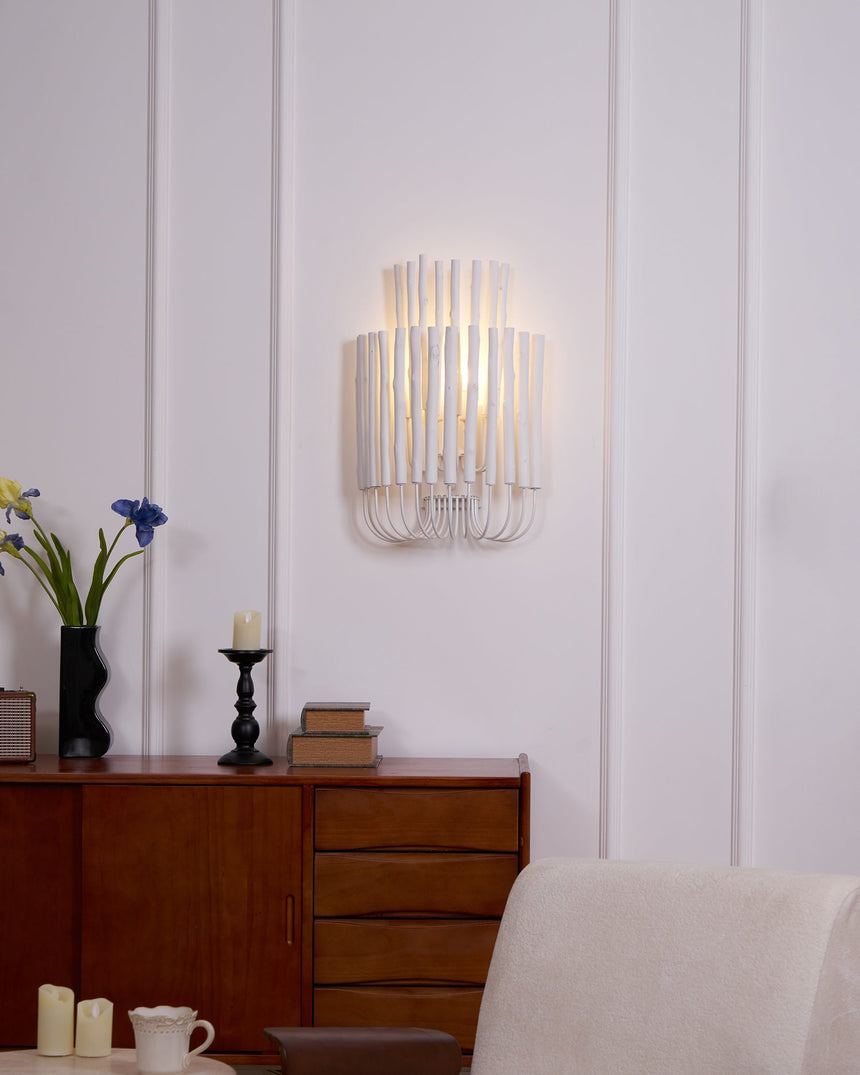 Rod sconce lit above a mid century sideboard beside an upholstered chair