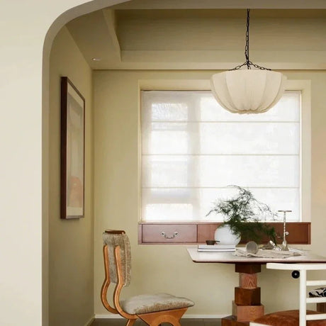 Gathered fabric shade lit above a round table in a warm room