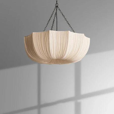 Gathered fabric shade lit softly against a pale wall
