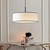 Fabric drum pendant light lit above a dining table set with glasses