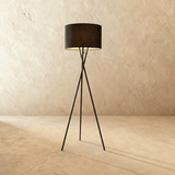 The same crossed tripod carrying a black fabric drum shade above three thin legs