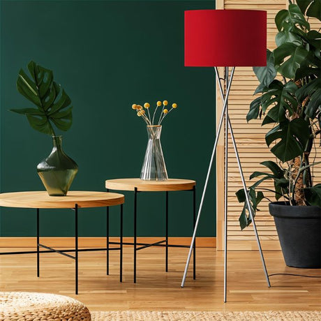 The red shade lit against a green wall beside two round tables and a plant